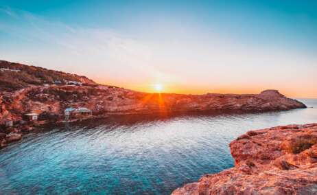 brown rocky mountain beside body of water during sunset
