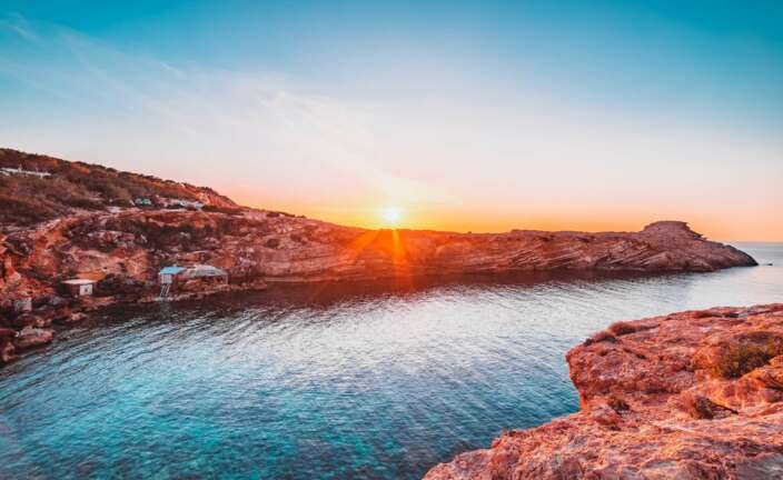 brown rocky mountain beside body of water during sunset